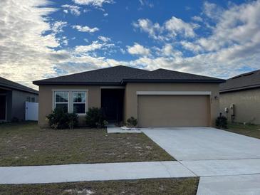 Single-story house with a two-car garage and landscaping at 1075 Aerides Way, Davenport, FL 33837