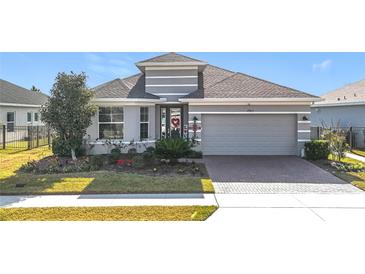 Gray one-story house with a landscaped front yard and a brick driveway at 17863 Passionflower Cir, Clermont, FL 34714