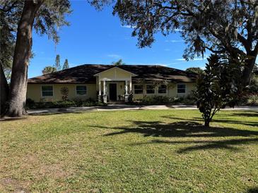 Beautiful yellow house with a large green lawn and mature trees at 825 E Lakeshore Blvd, Kissimmee, FL 34744