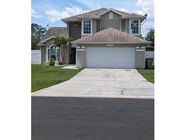 Two-story house with a white garage door and landscaped lawn at 1424 Sophie Way, Kissimmee, FL 34744