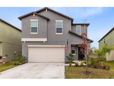 Two-story house with gray siding, beige garage door, and landscaping at 1791 Yellow Trl, Lakeland, FL 33801