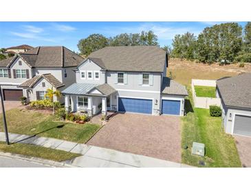 Two-story house with gray exterior, blue garage doors, and landscaped yard at 2230 Standing Rock Cir, Oakland, FL 34787