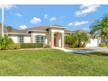 One-story house with red door, palm trees, and well-manicured lawn at 3206 Bay View Ct, St Cloud, FL 34772