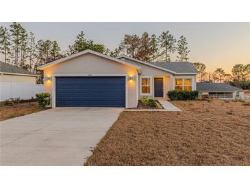 Single-story house with a navy blue garage door and well-manicured lawn at 386 Marion Oaks Trl, Ocala, FL 34473