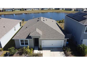 Aerial view of a single-story house with a white garage door and a lake behind it at 522 Noble Ave, Davenport, FL 33837