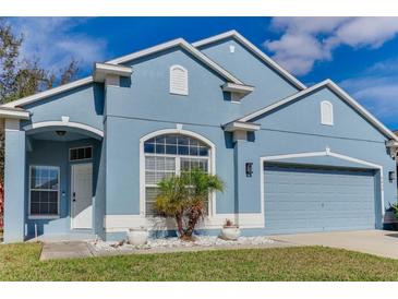 Beautiful blue house with a two-car garage and well-manicured lawn at 9850 Hidden Dunes Ln, Orlando, FL 32832