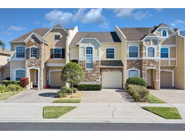 Three-story townhouses with stone accents and attached garages at 1009 Wood Cv, Kissimmee, FL 34743