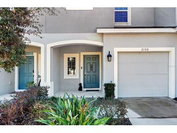 Townhouse exterior featuring a gray facade, two-car garage, and landscaping at 2106 Crystal Bell St, Orlando, FL 32824