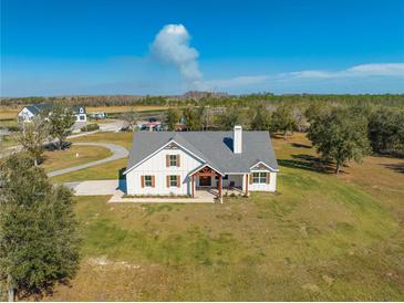 Aerial view of a charming farmhouse on a spacious lot with mature trees at 3449 N Canoe Creek Rd, Kenansville, FL 34739