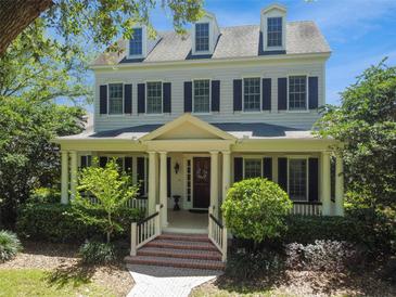 Two-story house with a wrap-around porch, brick pathway, and lush landscaping at 510 Golfpark Dr, Celebration, FL 34747