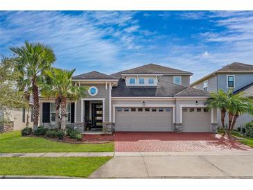 Two-story house with a gray exterior, red brick driveway, and palm trees at 3040 Cardillino Way, Kissimmee, FL 34741