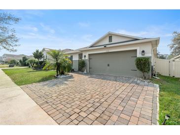 Exterior view of a house with a brick driveway and palm tree at 6364 Domenico Ct, Groveland, FL 34736