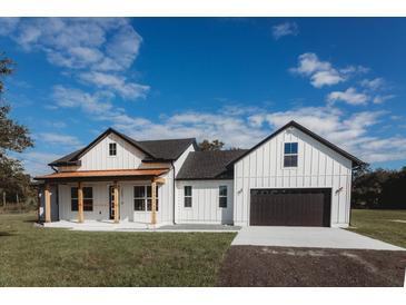 Beautiful farmhouse with a white facade, dark roof, and a front-facing garage at 0 Orangewood Ave, St Cloud, FL 34772