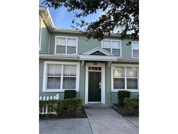 Charming townhouse with a dark green front door, white trim, and manicured landscaping at 4010 San Gallo Dr # 105, Kissimmee, FL 34741