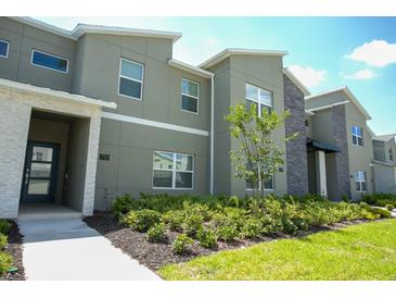 Modern townhome with a well-maintained landscape and stone detailing at 750 Pebble Beach Dr, Davenport, FL 33896