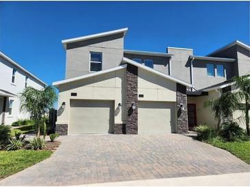 Modern townhome boasts a two-car garage, stone accents, and a neutral color scheme, exuding curb appeal at 8885 Cabot Cliffs Dr # 103, Davenport, FL 33896