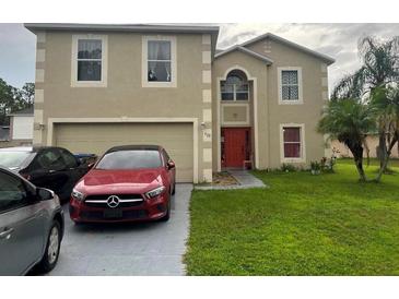 Two-story home featuring a two car garage and an orange front door at 920 Gillingham Ct, Kissimmee, FL 34758