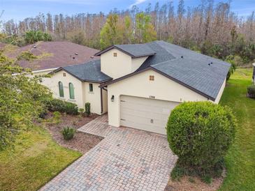 Well-maintained single-Gathering home featuring brick paved driveway, attached two-car garage, and manicured landscaping at 1398 Del Mar Dr, Kissimmee, FL 34759