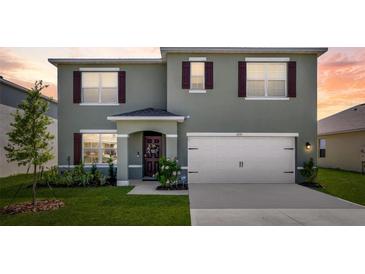 Two-story home featuring a two-car garage, manicured lawn, and charming front entrance at 1755 Buckeye Rd, Davenport, FL 33837