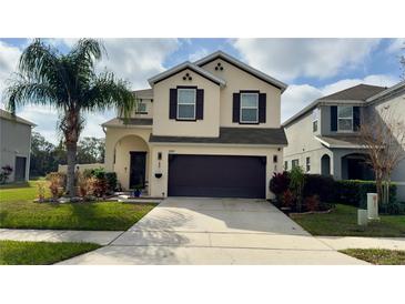 Two-story home featuring a two-car garage, manicured lawn and tropical palm tree at 3199 Turret Dr, Kissimmee, FL 34743
