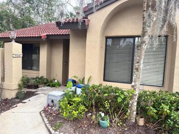 Charming home exterior with a red tile roof, lush landscaping, and beautiful architectural details at 466 Club Dr, Winter Springs, FL 32708