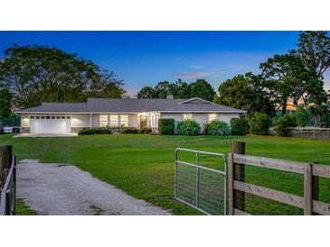 Charming single-story home with a manicured lawn and a welcoming gated entrance at twilight at 6845 Old Melbourne Hwy, St Cloud, FL 34771
