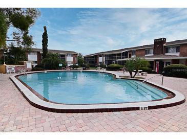 Community pool surrounded by lush landscaping near brick buildings under a sunny sky at 777 W Lancaster Rd # A-13, Orlando, FL 32809