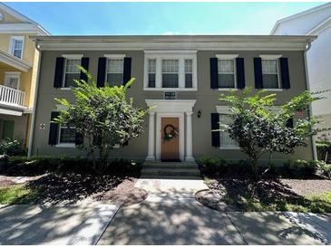 Charming two-story townhouse with black shutters, complemented by beautiful landscaping and a welcoming front entrance at 1017 Siena Park E Blvd, Celebration, FL 34747