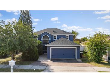 Two-story home featuring a dark blue exterior, well-maintained landscaping, and a paved driveway at 1067 Ronlin St, Haines City, FL 33844