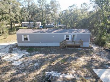 Exterior angle of a single-story home featuring light gray vinyl siding and a small deck with light brown wooden stairs at 11776 Nw 18Th Pl, Ocala, FL 34482