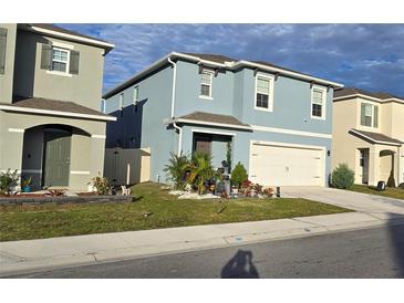 Charming two-story home boasts blue exterior, well-manicured lawn, and a two-car garage at 1292 Cascades Ave, Davenport, FL 33837