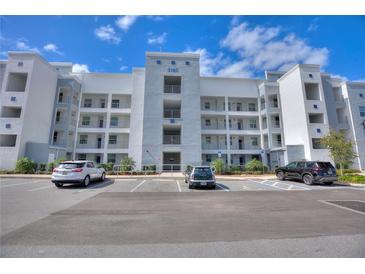 View of a modern condo building with well-maintained landscaping and ample parking under a sunny sky at 3180 Paradoux Circle # 205, Kissimmee, FL 34746