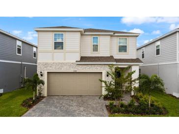 Charming two-story home featuring stone accents, a two-car garage, and meticulously landscaped front yard at 3348 Lilac Way, Davenport, FL 33897