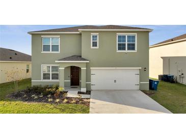 Two-story home with a spacious two car garage, neutral colored stucco and inviting front yard at 417 Noble Ave, Davenport, FL 33837