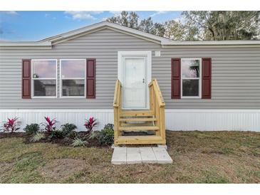 Charming home exterior with gray siding, red shutters, and well-manicured landscaping at 4628 Chicadee Ave, Orlando, FL 32812