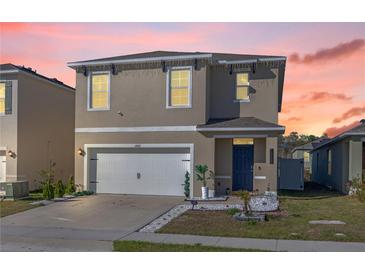 Two-story home featuring a two-car garage, blue front door, well-manicured lawn, and tasteful landscaping at 1368 Berry Ln, Davenport, FL 33837