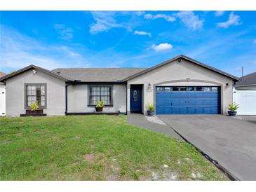 Charming single-story home with manicured lawn, blue garage door, and attractive landscaping at 1464 Howland Blvd, Deltona, FL 32738