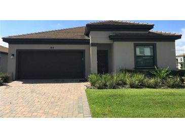 Charming single-story home with a well-manicured lawn, a paved driveway, and a two-car garage at 194 Aidans Lndg, Haines City, FL 33844