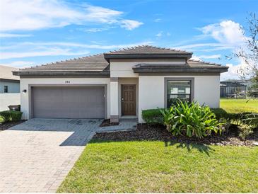 Charming one-story home featuring a two car garage, tiled roof, and well-manicured lawn at 194 Aidans Lndg, Haines City, FL 33844