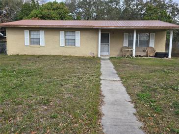 A charming single-story home features a metal roof, white shutters, and a cozy front porch at 2227 Virginia Dr, Kissimmee, FL 34741