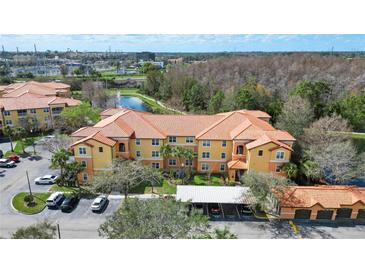 Aerial view of multi-Gathering home complex with a pond, fountain, mature trees, and covered parking at 5463 Vineland Rd # 5107, Orlando, FL 32811