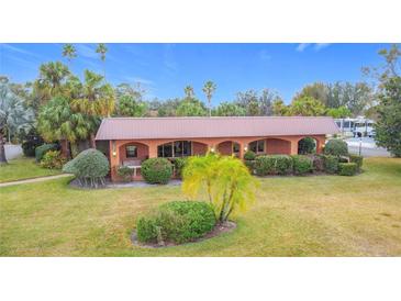 Charming brick home featuring mature landscaping, a low-pitch roof, and an inviting arched front porch at 6 Palm Way, Haines City, FL 33844