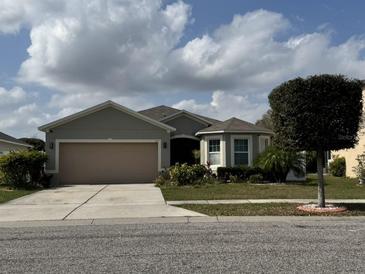 Charming single-story home with a well-maintained lawn, mature landscaping, and an attached two-car garage at 112 Lake Tracy Ct, Haines City, FL 33844
