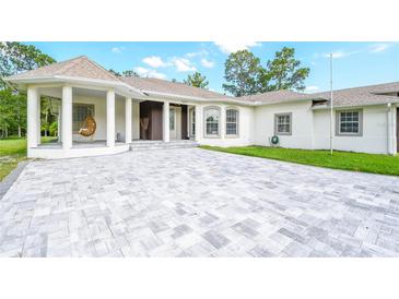 Elegant home featuring a hanging chair on the front porch and a large paved driveway at 12177 Gray Birch Cir, Orlando, FL 32832