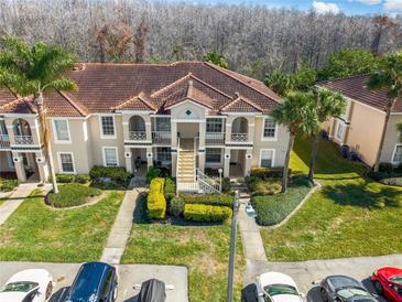 Inviting condo building featuring lush landscaping, red tile roof, and convenient parking spaces at 13829 Timberland Dr # 204, Orlando, FL 32824