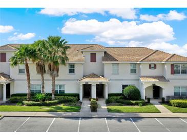 Well-maintained condo exterior features lush landscaping, palm trees, and a tile roof at 1554 Plunker Dr, Davenport, FL 33896