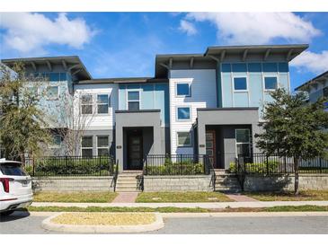 Modern townhomes with stylish blue and white exterior, well-maintained landscaping and black metal fences at 7381 Alpine Butterfly Ln, Orlando, FL 32819