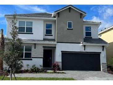 Two-story home showcasing a sleek, modern design with a dark gray garage door and neutral color palette at 2402 Rama Dr, Kissimmee, FL 34746