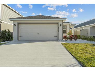 View of the garage, driveway, and front lawn with landscaping at 3930 Palazzo Pl, Winter Haven, FL 33884