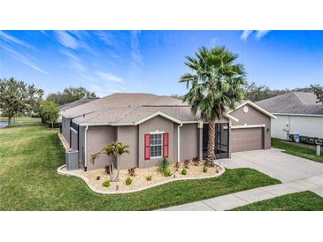 Charming single-story home features a well-manicured lawn, a palm tree, and a two-car garage at 901 Shorehaven Dr, Poinciana, FL 34759